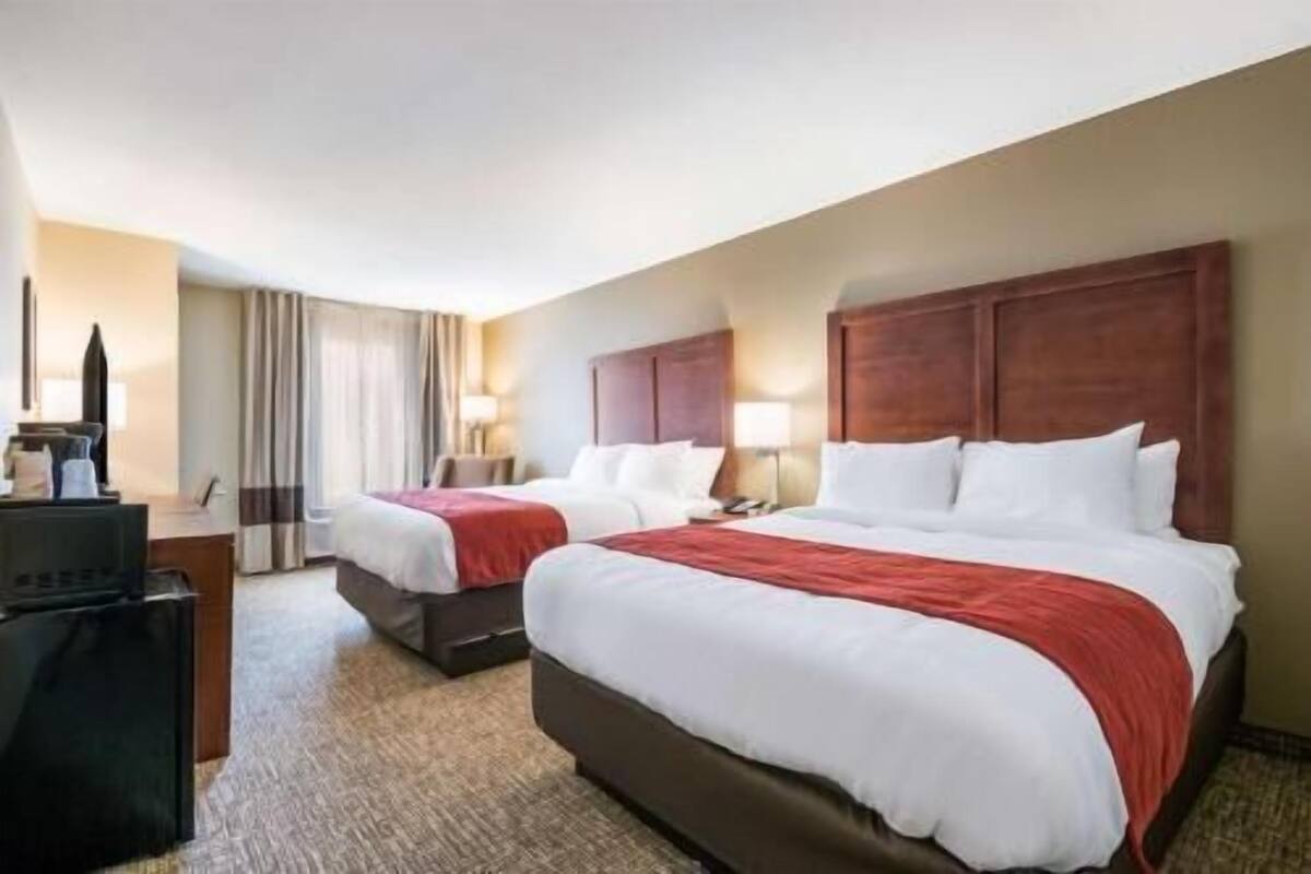 Une chambre d’hôtel avec deux lits, un bureau, une chaise et un téléviseur.