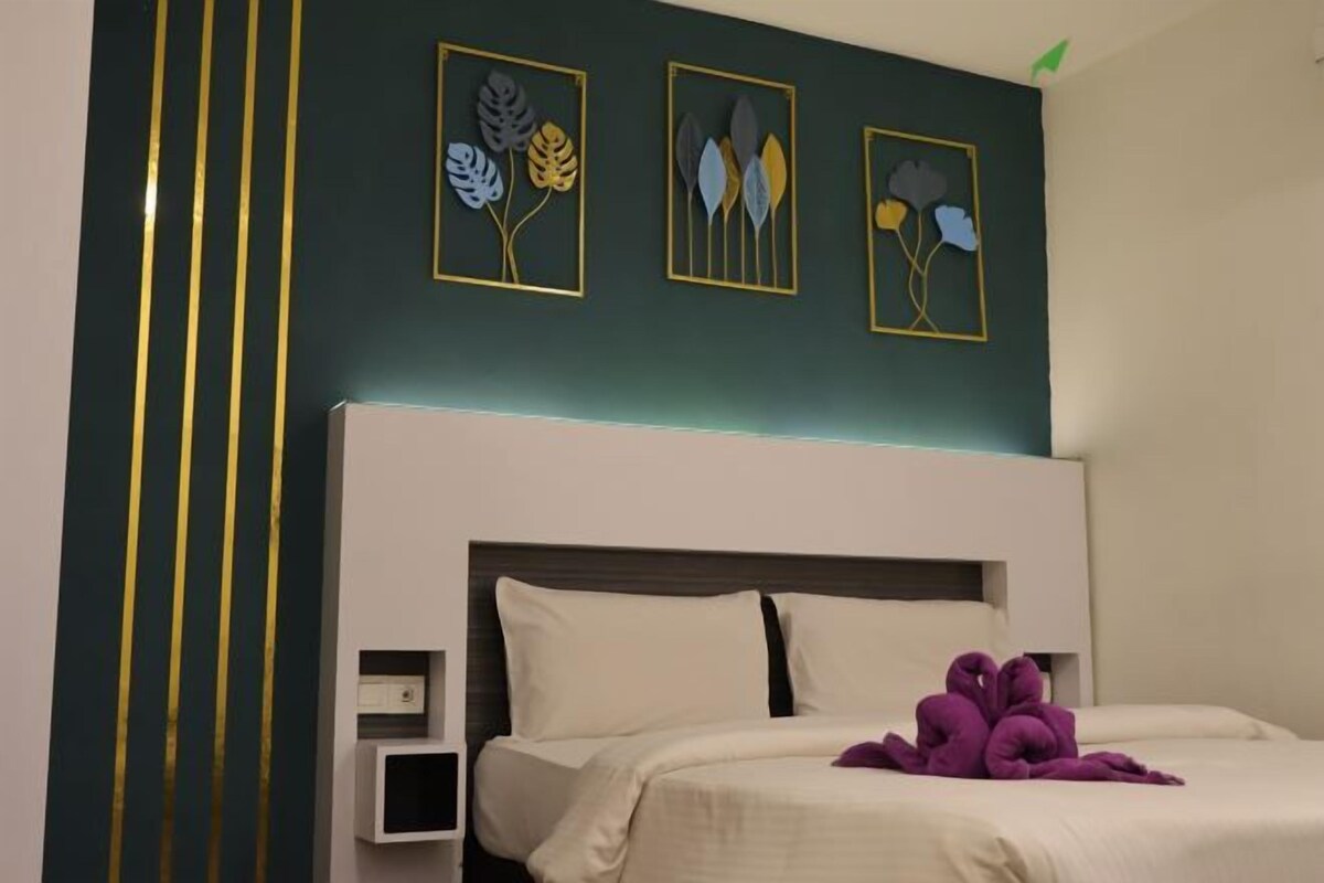 A hotel room with a bed, a nightstand, and wall art.
