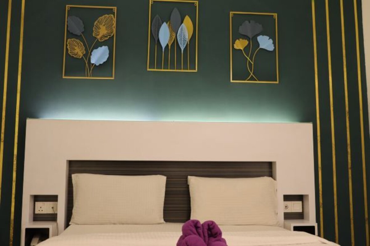 Una habitación de hotel con una cama, dos mesitas de noche y tres cuadros con motivos florales en la pared.