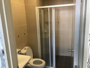 A bathroom with a toilet, a shower enclosure, and tiled walls. - KL Taragon Apartment (Kuala Lumpur)