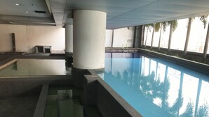 Une piscine intérieure à l’eau claire, entourée de piliers et de murs en béton.