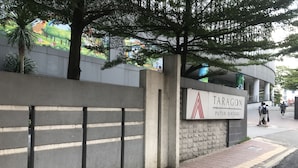 Une enseigne pour Taragon Puteh Bintang, avec un mur en béton et un trottoir carrelé.