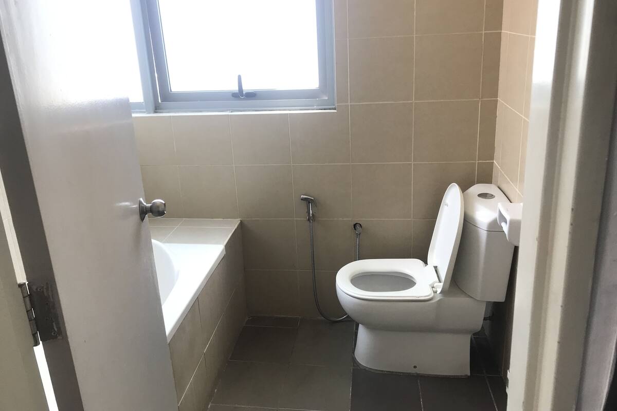 A small bathroom with a bathtub, toilet, and a window.