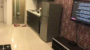 Une cuisine moderne équipée d’un réfrigérateur, d’un four à micro-ondes et d’un évier. Un téléviseur fixé au mur affiche du texte.