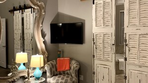 Une pièce avec un grand miroir, un téléviseur, un fauteuil à motifs et une porte coulissante de style rustique.