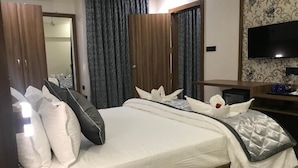 A hotel room with a large bed, a TV, a desk, and a wardrobe.