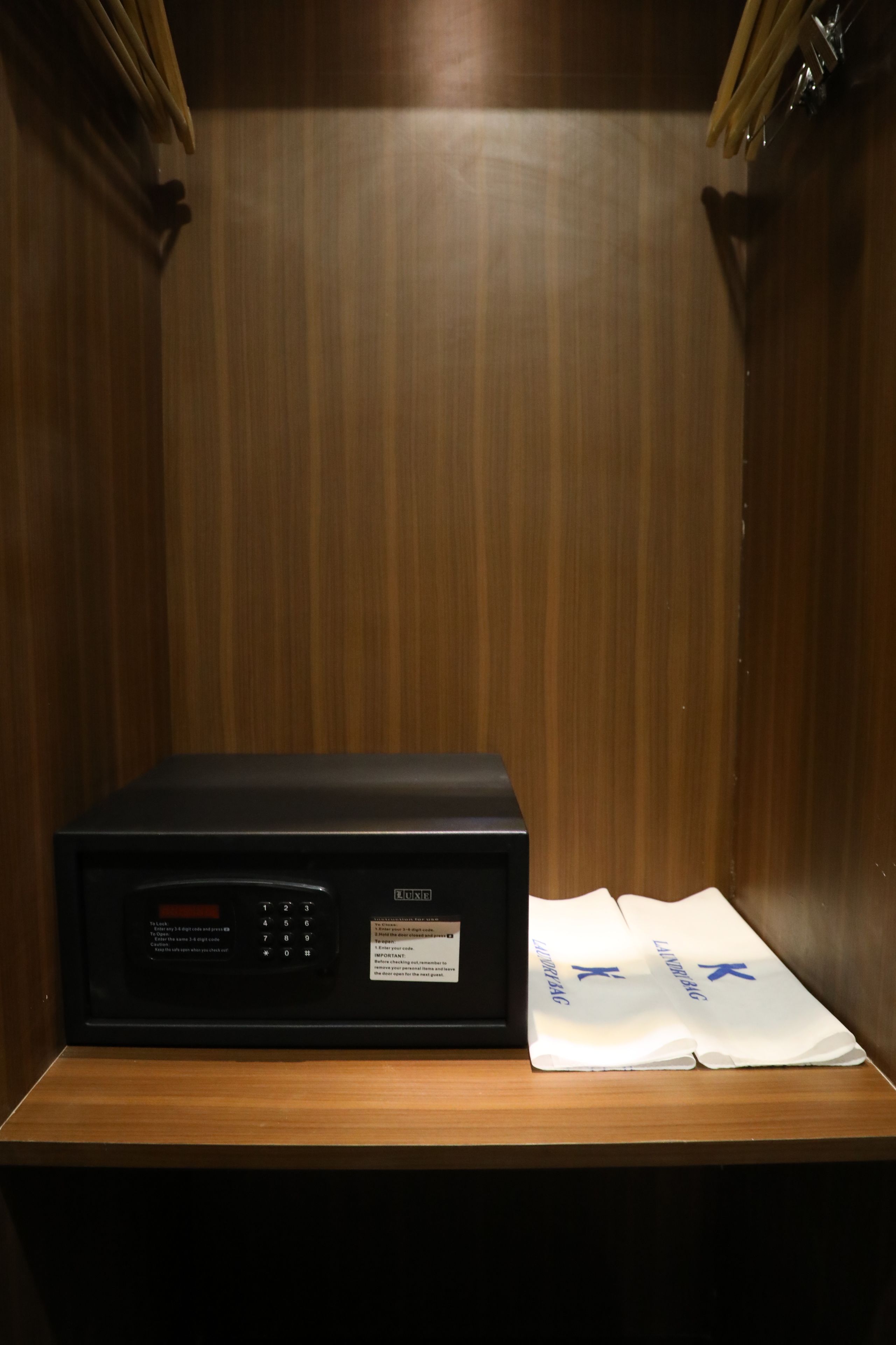 A room with a wooden panel wall, a black electronic device on a wooden table, and two white towels with blue text.