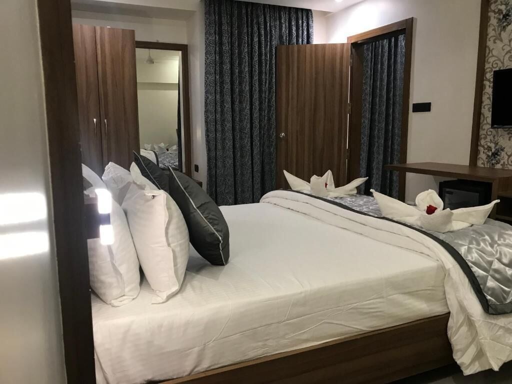 A neatly made bed with white and dark pillows, a wooden headboard, and a bedside table with a lamp.