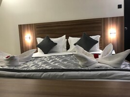 Una cama bien hecha con cubrecama acolchado, dos almohadas y una decoración de toallas.