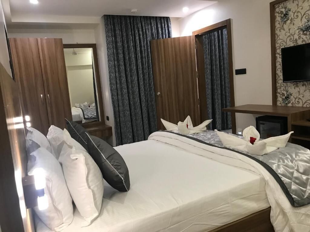 Una habitación de hotel con cama, armario de madera, cortinas, escritorio y televisor.