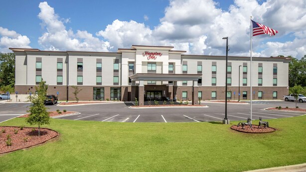 A Hampton Inn hotel with a parking lot, a flag, and a statue.