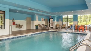 An indoor pool with clear signage for pool emergency cut-off switch, a lifeguard chair, and a pool depth marker.