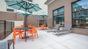 An outdoor patio with tables, chairs, and umbrellas. - Hampton Inn Camden (Camden)