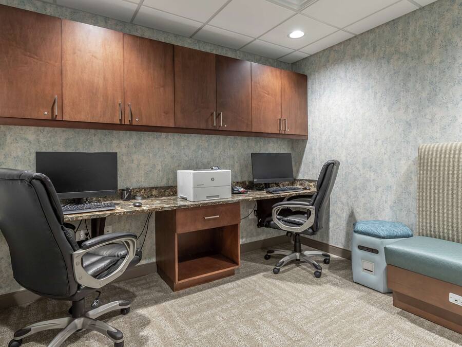 A professional office space with two desks, chairs, a printer, and a massage table.