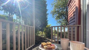 A balcony with a table, two mugs, and a plate of macarons.