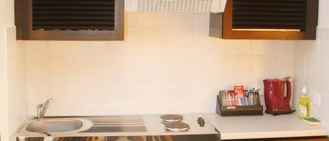 A compact kitchen with a sink, stove, and cabinets.