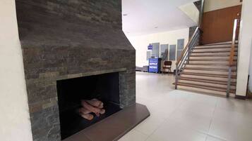 A modern interior with a stone fireplace, a staircase, and a reception desk.