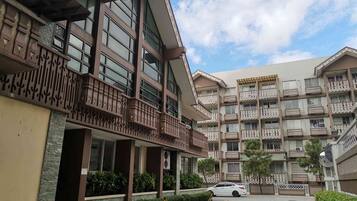 A multi-story hotel with balconies, a parking area, and a clear sky.