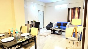 A modern living room with a dining area, a sofa, a coffee table, and a lamp. - Namaha Stays (Hyderabad)