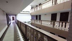 Un couloir d’hôtel avec une allée centrale bordée de balcons dotés de rampes décoratives.