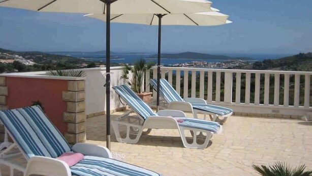 A terrace with lounge chairs and a large umbrella, overlooking a coastal landscape. - Villa with air conditioning, terrace and outdoor pool (Rogoznica)
