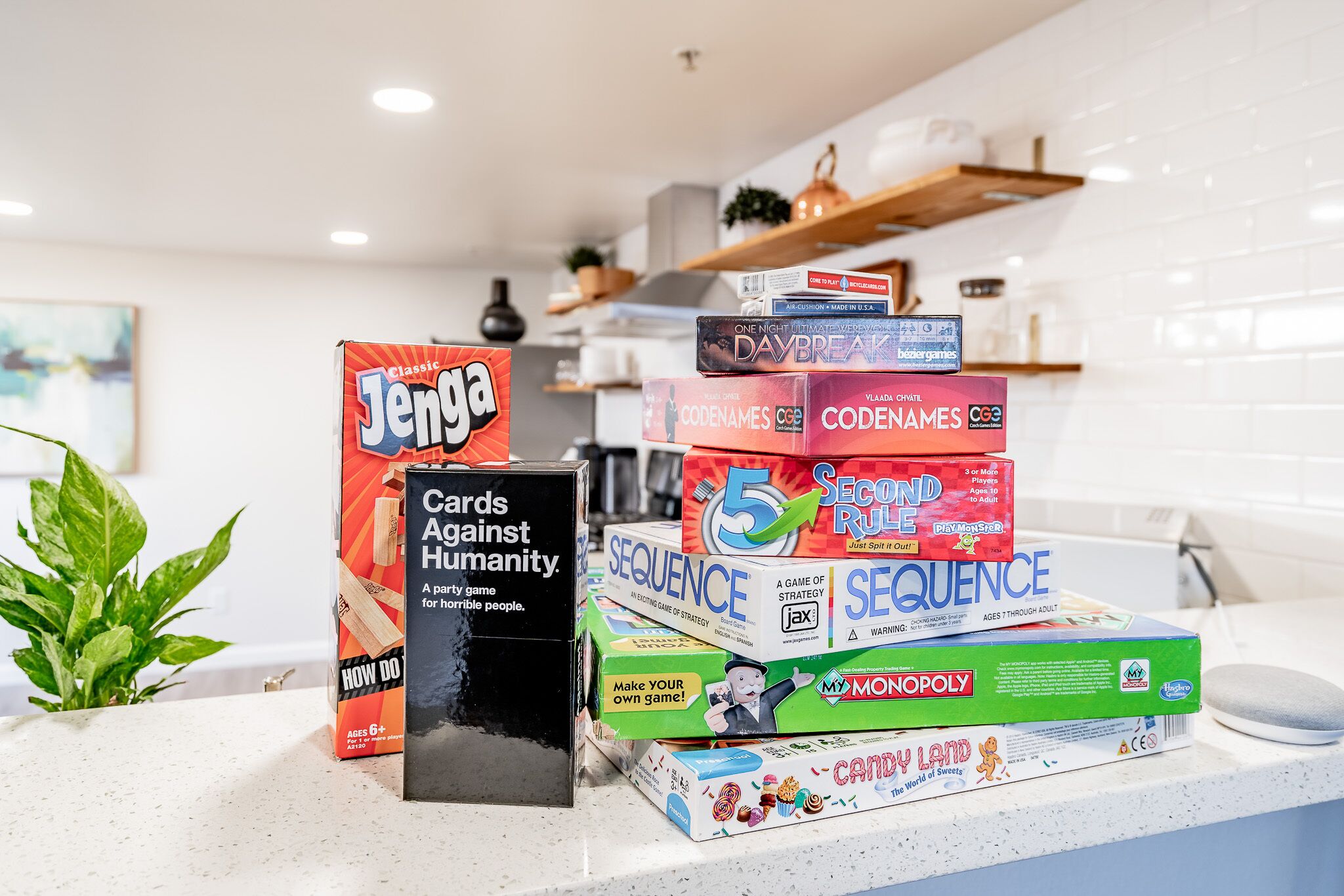 A stack of board games on a kitchen counter.