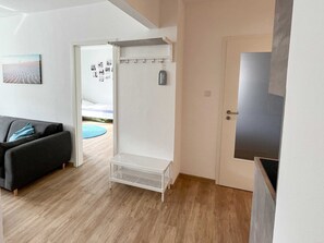 A modern living room with a dark sofa, a white door, and a small white shelf unit. - Apartment house Nige Ooge Apartment No. 1 - Apartment with small terrace (Cuxhaven)