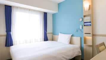 A hotel room with a large bed, a desk, a chair, a nightstand, a wall clock, and a wall-mounted lamp.