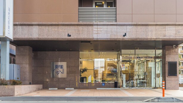 A modern building with a glass entrance, a visible sign for a hotel, and a ramp leading to the entrance.