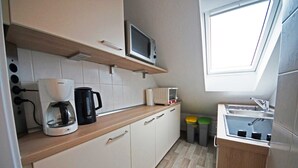 Cocina compacta con microondas, cafetera y lavabo.