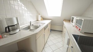 Eine Küche mit Kaffeemaschine, Spüle, Mikrowelle und einem Fenster für natürliches Licht.