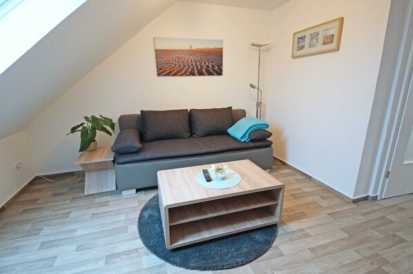 A modern living room with a sofa, a coffee table, a plant, and a painting on the wall.