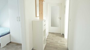 Ein Flur mit einem Bett, einem Kleiderschrank und einem Spiegel an der Wand.