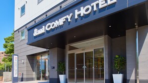 The exterior of the Sand Comfy Hotel with a modern facade, large glass entrance, and potted plants. - &and COMFY HOTEL Kumamotojo View (Kumamoto)