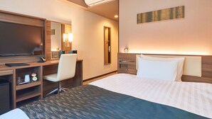 A hotel room with a bed, a desk, a chair, a TV, a mirror, a clock, and a wall-mounted light. - &and COMFY HOTEL Kumamotojo View (Kumamoto)