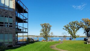 A modern building with a stone facade and large windows overlooking a body of water.