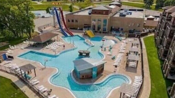 A swimming pool with a slide, lounge chairs, and a small building.