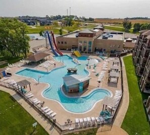 Una piscina con tobogán, sillas de descanso y un pequeño edificio.