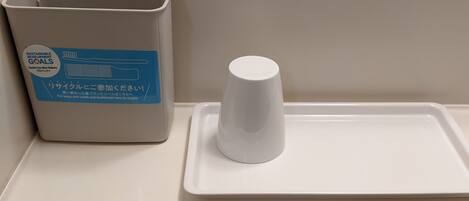 A bathroom sink with a trash bin and a cup holder.