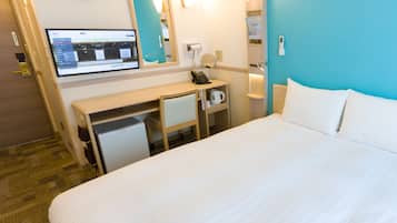 Una habitación de hotel con una cama, un escritorio, una computadora, un reloj y un espejo.