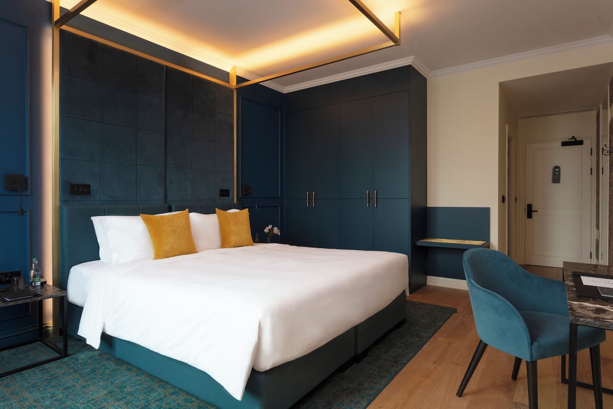 A modern bedroom with a large bed, a desk, and a chair.