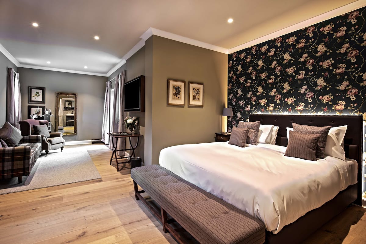 A bedroom with a large bed, a bench, a sofa, and a TV.