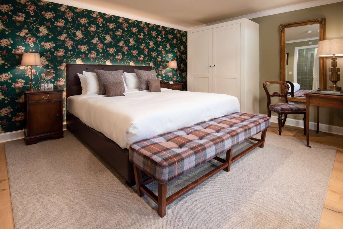 A bedroom with a large bed, a bench, a nightstand, a chair, and a dresser.