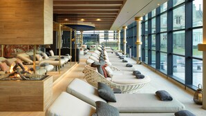 A modern lounge area with a fireplace, comfortable seating, and large windows offering views of the outside.