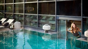 A swimming pool with clear water, lounge chairs, and a modern building with large windows in the background.