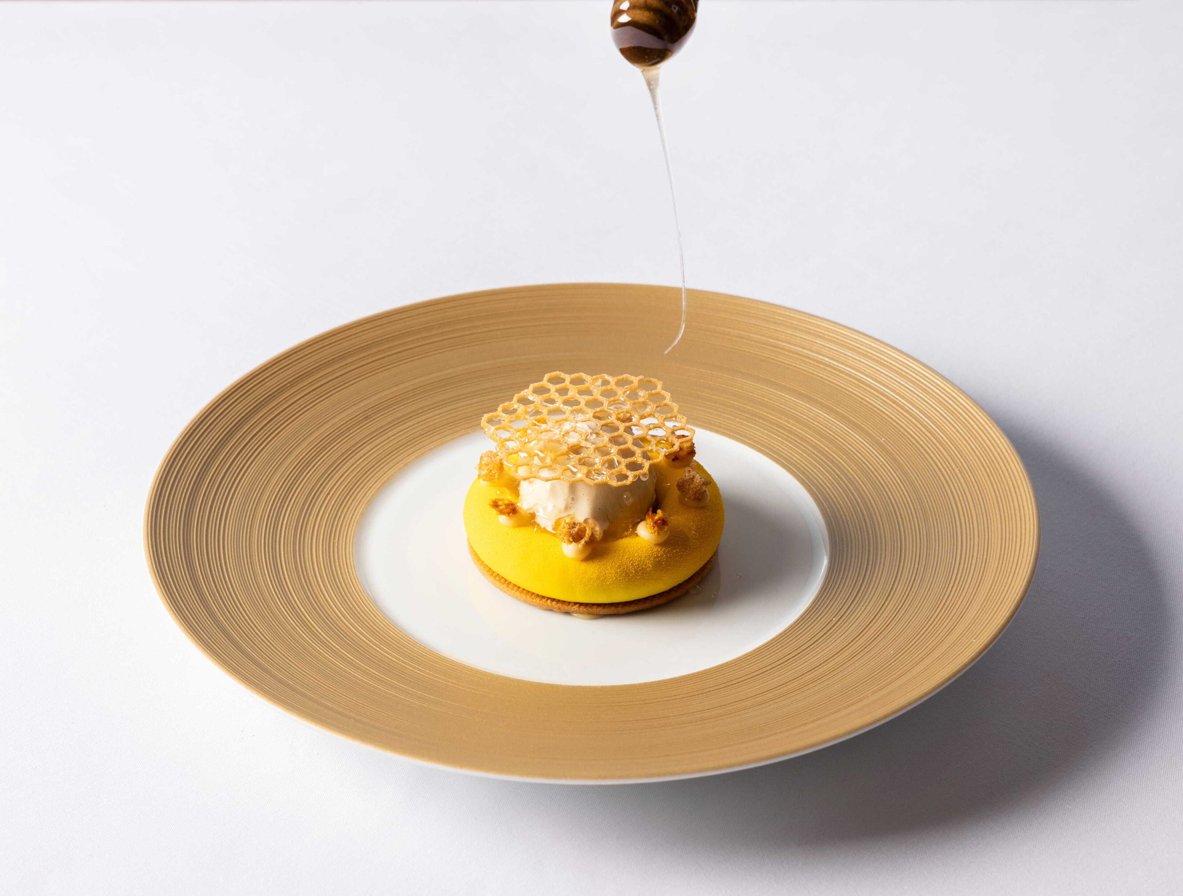 Un postre en un plato con un chorrito de miel.
