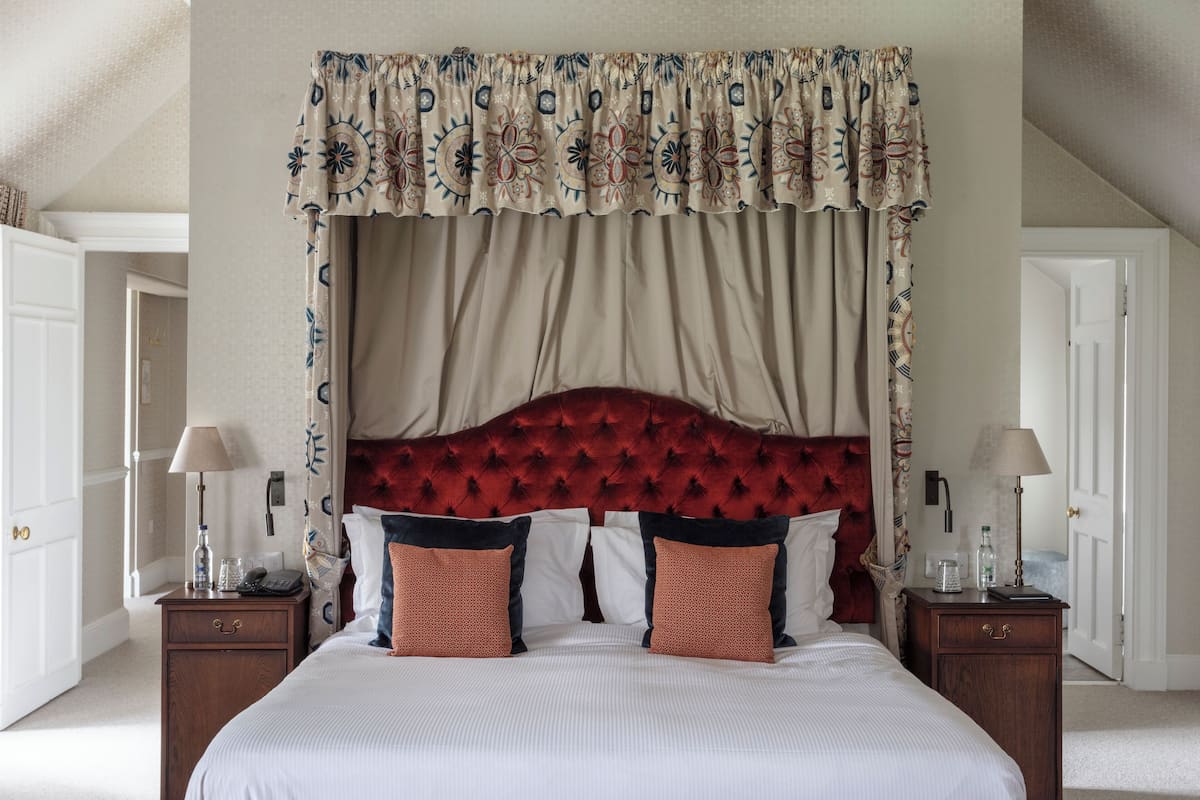 A bedroom with a tufted headboard, a canopy bed, and a nightstand with a lamp.