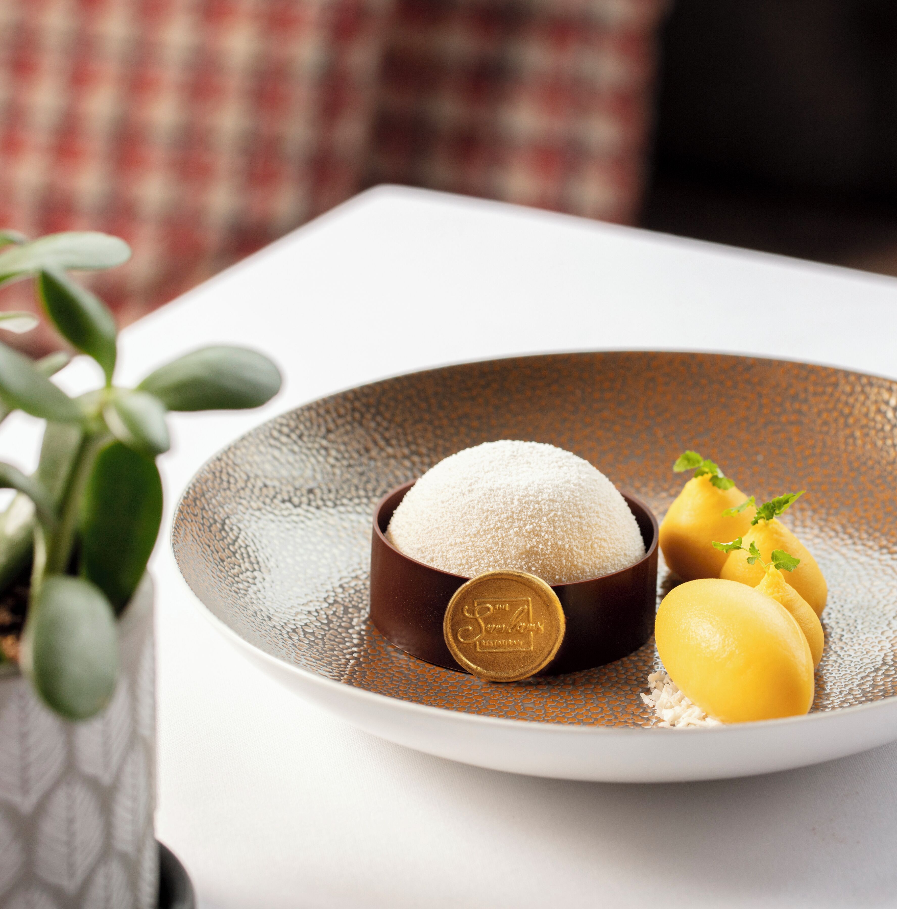 A dessert plate with a bowl of white powder, a coin, and two lemon slices on a textured plate.
