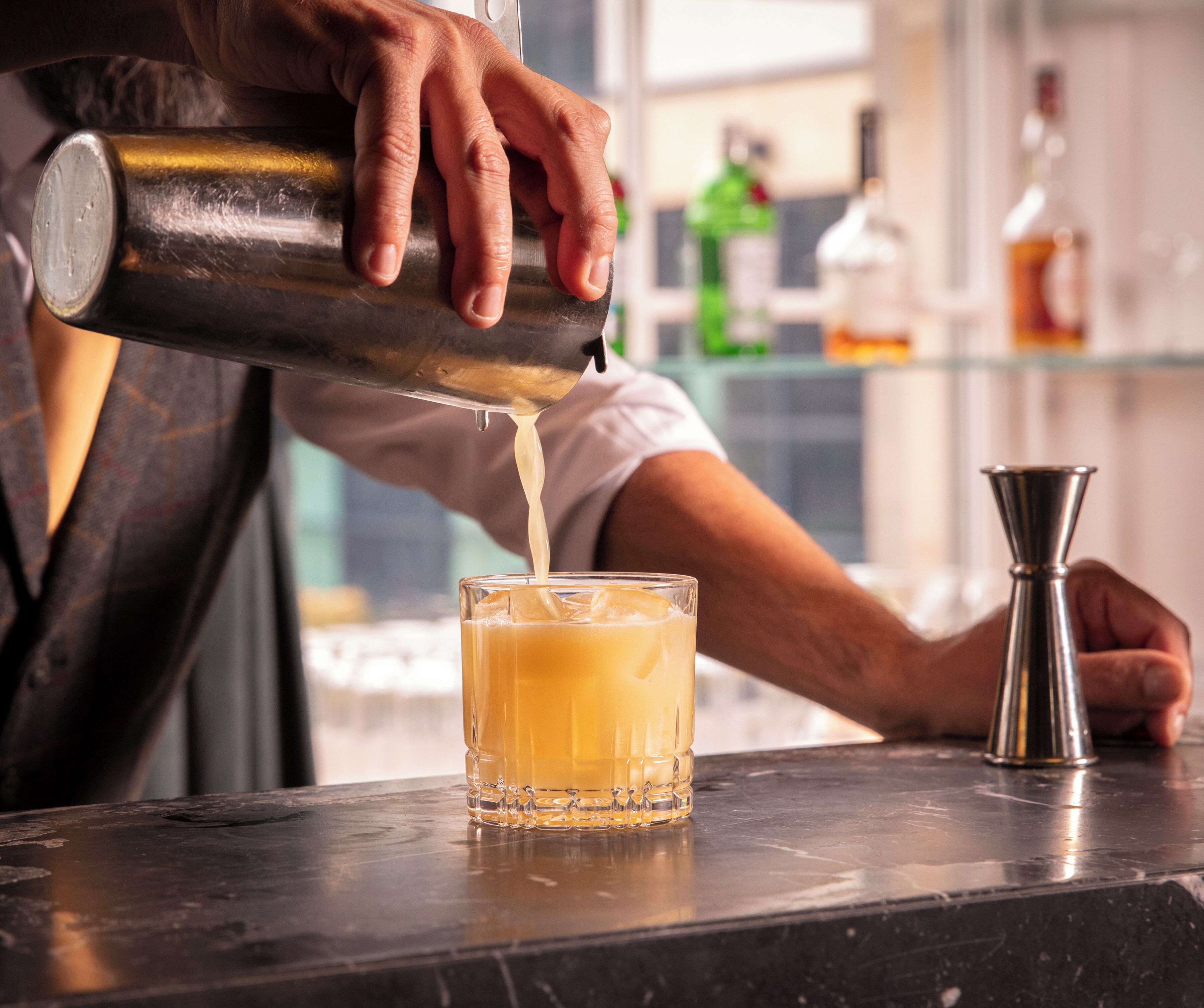 A bartender pouring a drink into a glass.