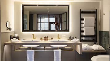 A modern bathroom with two sinks, a large mirror, and a bathtub.